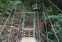 田立の滝登山道吊橋（新設工事）・長野県木曽郡南木曽町田立地内駐車場から約1時間歩いた当たり。霧ヶ滝の西側。急な階段を上ったところ。　主索を斜索に分散させ、1本当たりにかかる荷重を600kg以下に設計。設計積雪量250cm。　山頂方向に向かって。
